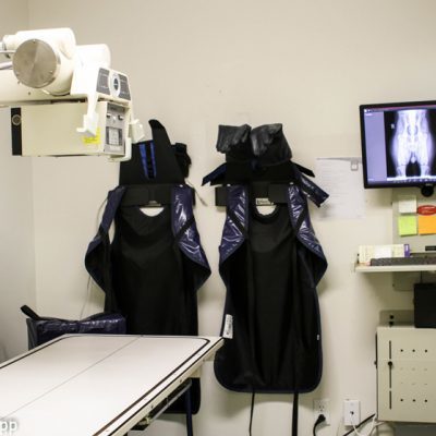 X-ray room at clinic. Pictured is x-ray machine as well as safety vests and computer with x-ray image on it